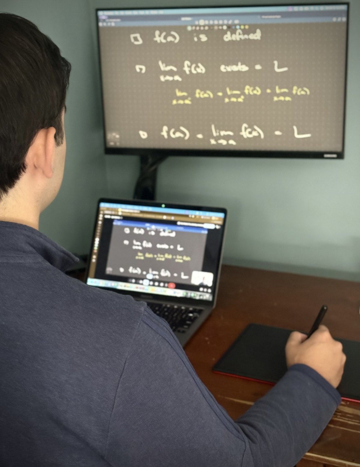 Arban using a pen tablet during a virtual math lesson, with handwritten work shared on his screens
